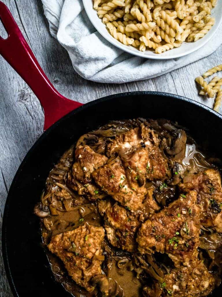 Chicken Marsala in a cast iron skillet with a side of pasta