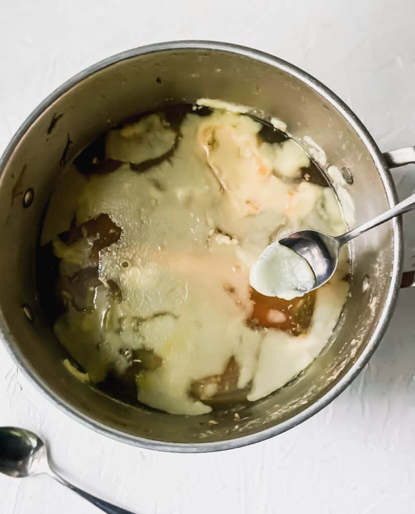 a spoon showing coagulated chicken fat on the top of the soup