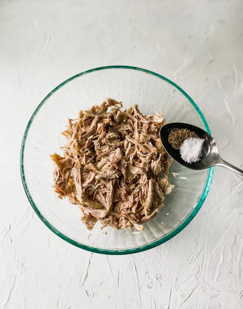 shredded chicken in a glass bowl with a spoon