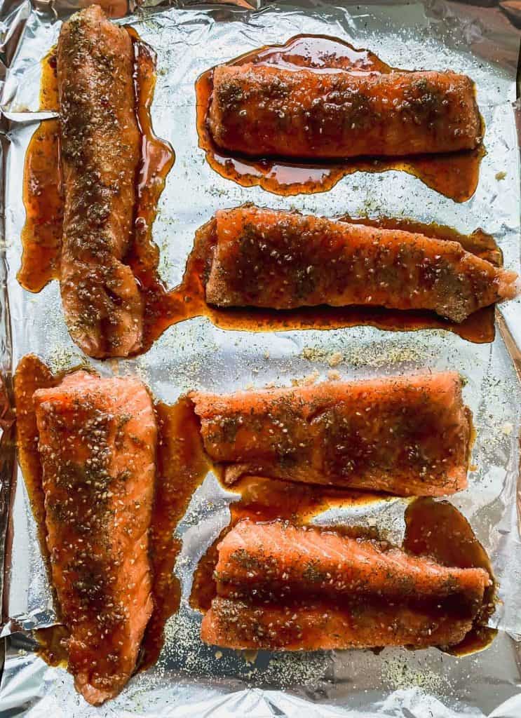 6 fillets on a foil lined sheet pan with seasonings and sauce on top.