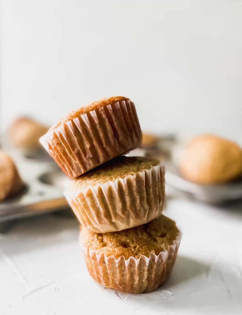 3 stacked muffins falling over with muffin pans behind them.