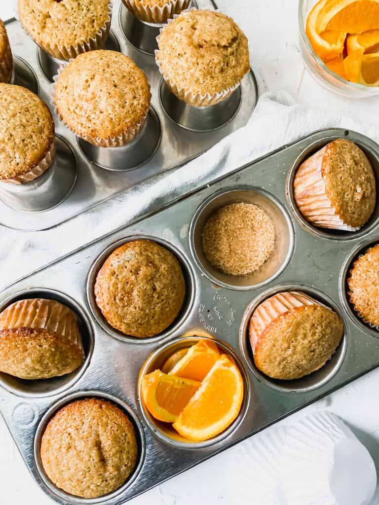 spiced orange muffins in muffin pans with coarse sugar and orange slices