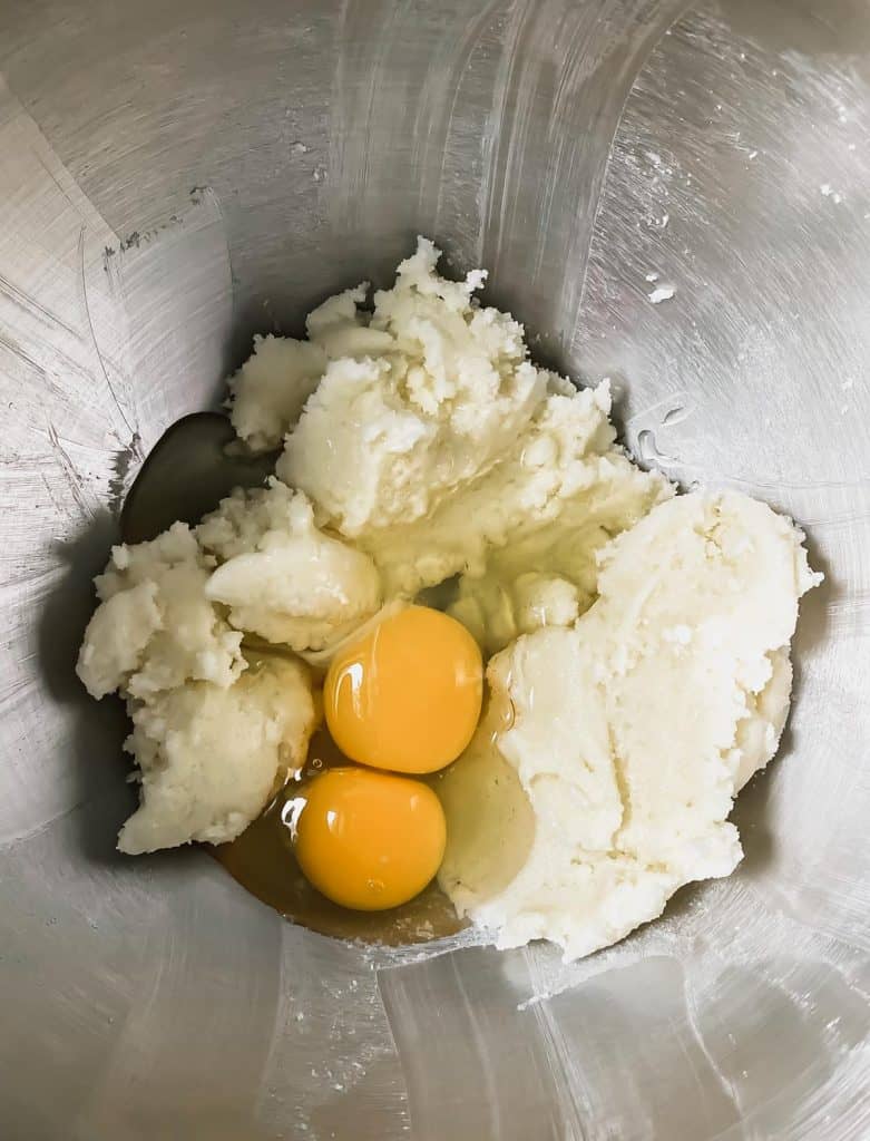 Beaten butter and sugar in a mixing bowl with 2 cracked eggs on top.