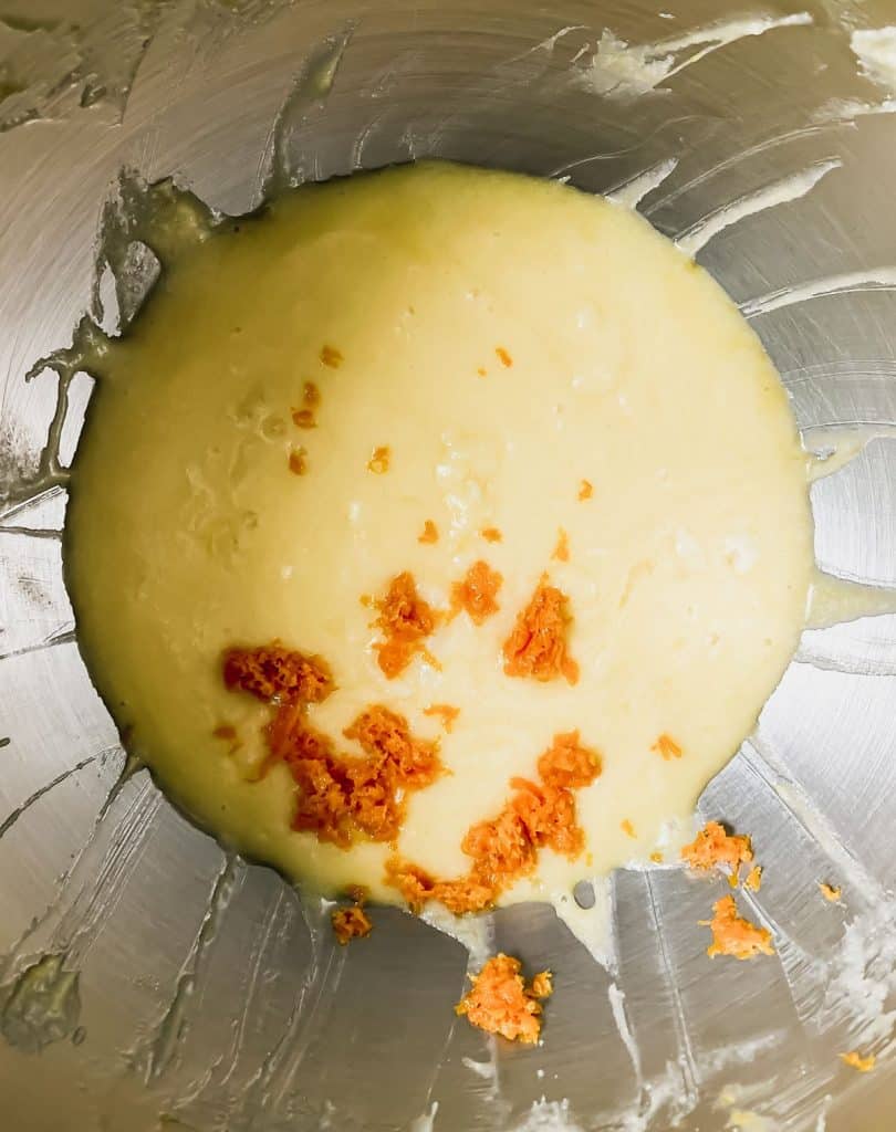 Muffin batter in a mixing bowl with orange zest on top.