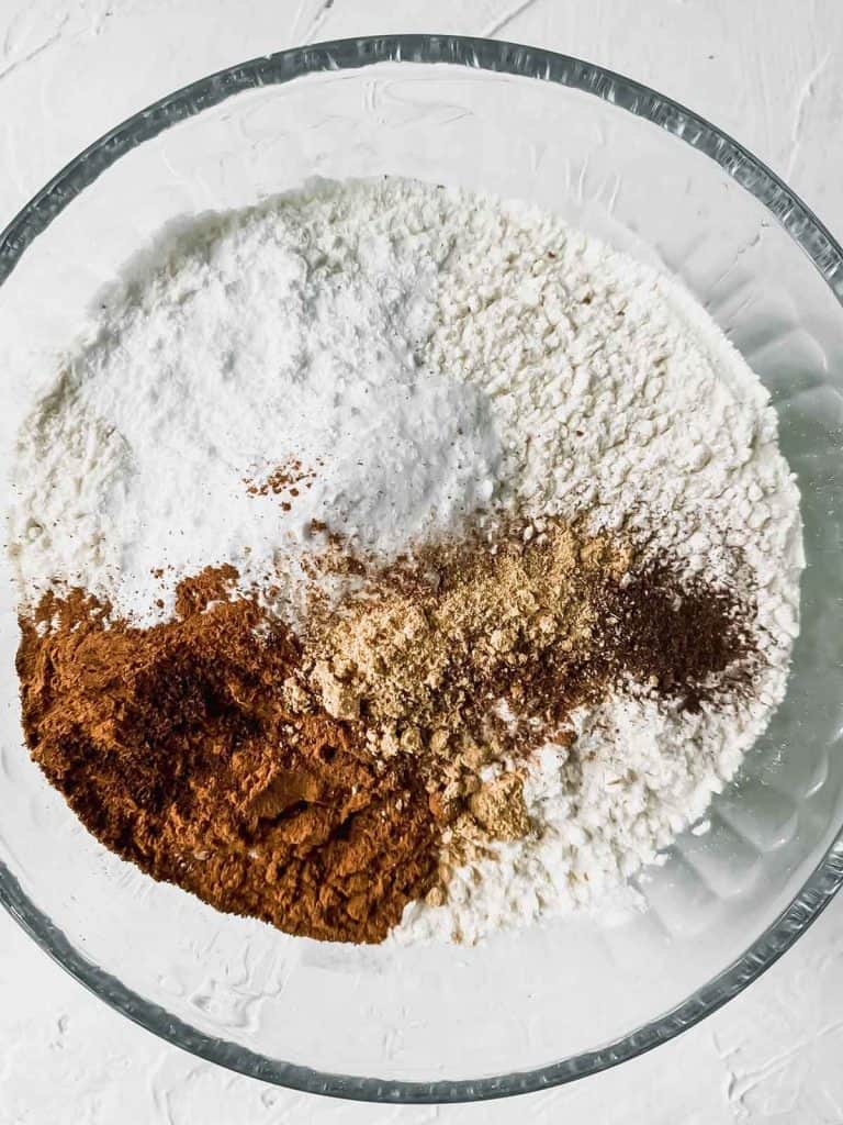 Dry ingredients for spiced orange muffins in a glass mixing bowl.