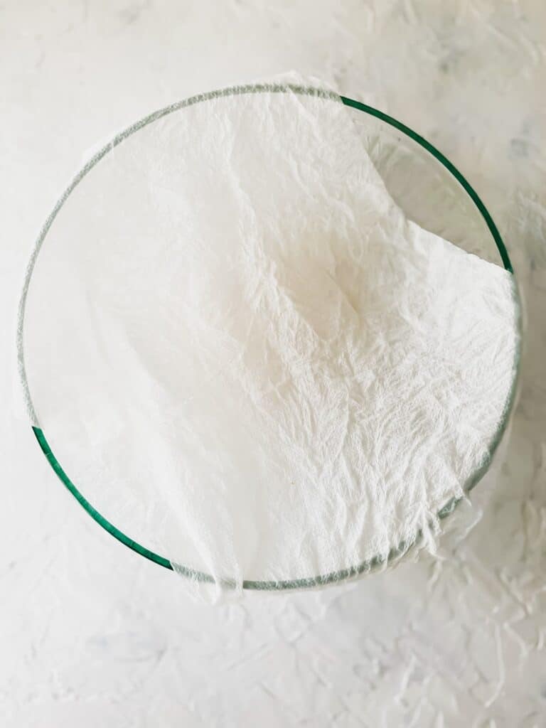 pizza dough in a bowl covered with a damp paper towel