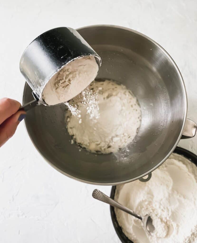 Adding flour to the yeast mixture with a 1 cup scoop